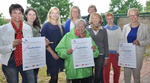 Die neue Netzwerk-Koordinatorin Maria Isabel Caceres Guerrero (links) präsentiert mit Vertretern der Netzwerkpartner das Plakat für das Stadtteilfest.